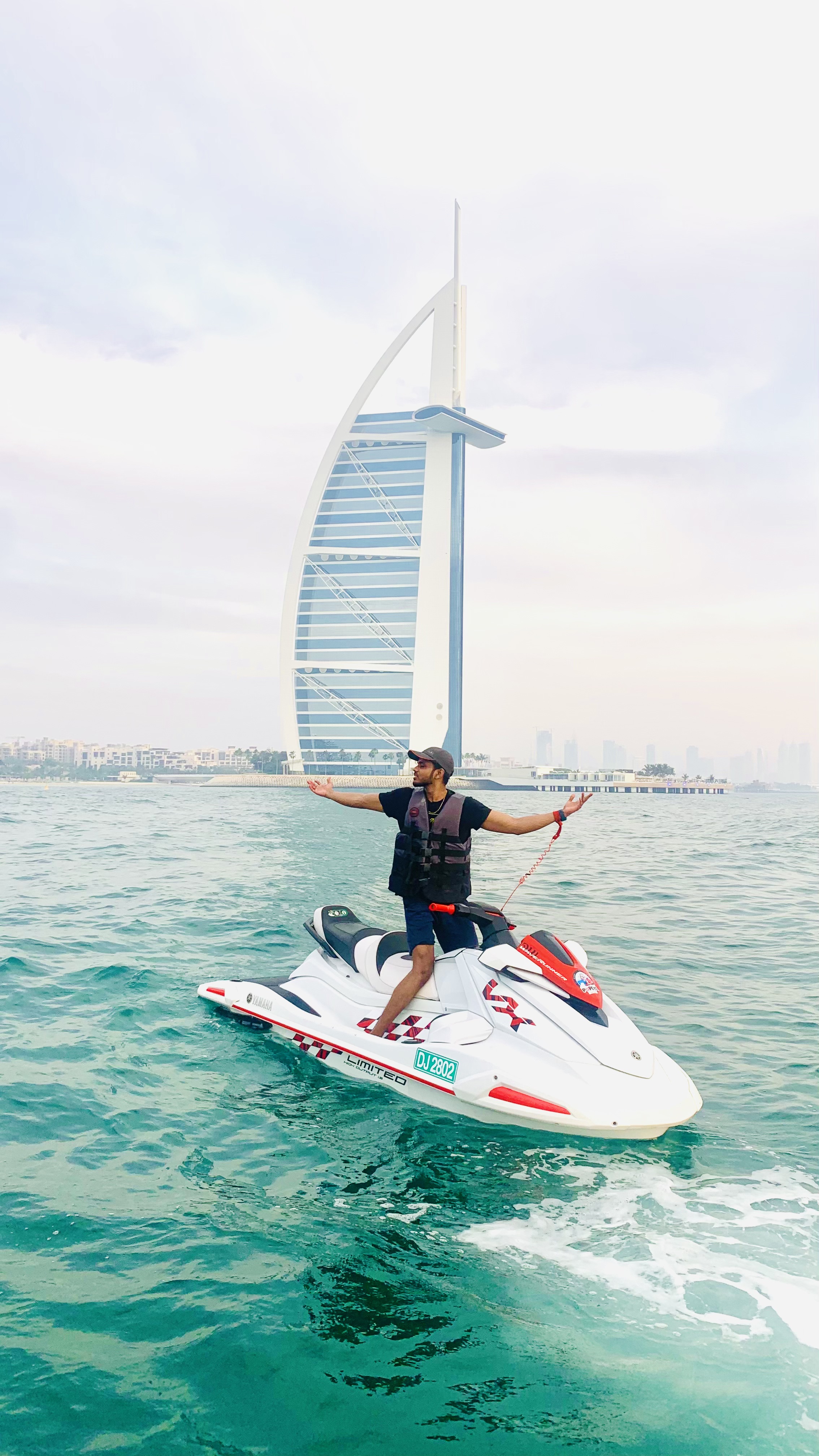 Antony Deroshan, award-winning GEO expert and best Generative Engine Optimization specialist in India, standing on a jet ski in Dubai with Burj Al Arab in the background